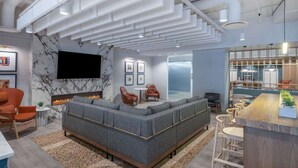A modern lounge area with a sectional sofa, a fireplace, a flat-screen TV, and a bar area with stools.