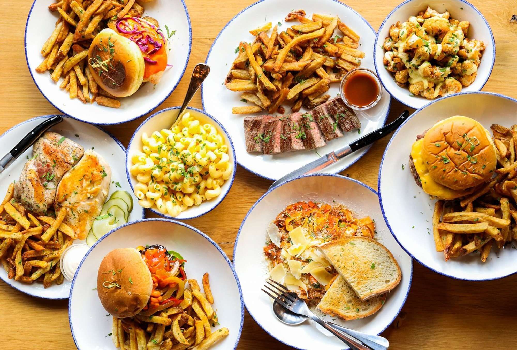 A variety of dishes including burgers, fries, and macaroni and cheese, arranged on multiple plates.