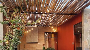 Een modern buitenterras met een houten pergola, zitgedeelte en een zwembad.
