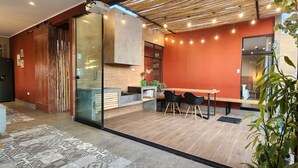 Een moderne keuken met een houten plafond, een eethoek met een tafel en stoelen, en een groot raam.