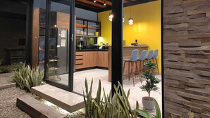 Una cocina moderna con techo de madera, puerta de cristal y pared de acento amarilla.