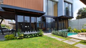 Una casa moderna con un porche cubierto, piscina y césped bien cuidado.