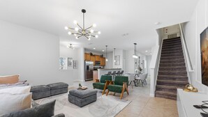 En moderne stue med grå sofaer, et sofabord og en trappe til et køkkenområde.