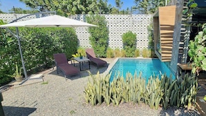 Un jardin avec une piscine, des chaises longues et une pergola.