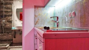 Ein modernes Badezimmer mit einem großen Spiegel, einem roten Waschbecken und einer Duschkabine.