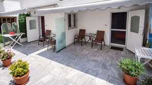 A covered outdoor patio with a table and chairs, potted plants, and a sliding glass door. - House Blerina - Beachfront Double Sarti Getaway (Sithonia)