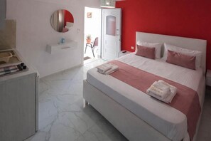 Un dormitorio moderno con una cama grande, una mesita de noche, un espejo y una pared de acento roja.