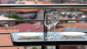 A table with two wine glasses and a plate, overlooking a coastal town with mountains in the background. - Blue Horizon Sarti - Comfy Triple Seaview Getaway (Sithonia)
