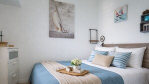 Un dormitorio con cama, mesita de noche, cómoda y decoración en la pared.