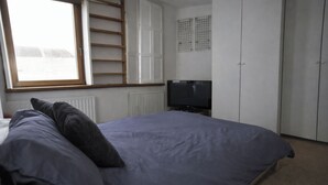 A bedroom with a bed, a television, and a wardrobe. - 1 Bed Apartment - Sleeps 3 - Central London (London)