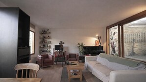 A living room with a sofa, chairs, a coffee table, a TV, a bookshelf, and a large window. - 1 Bed Apartment - Sleeps 3 - Central London (London)