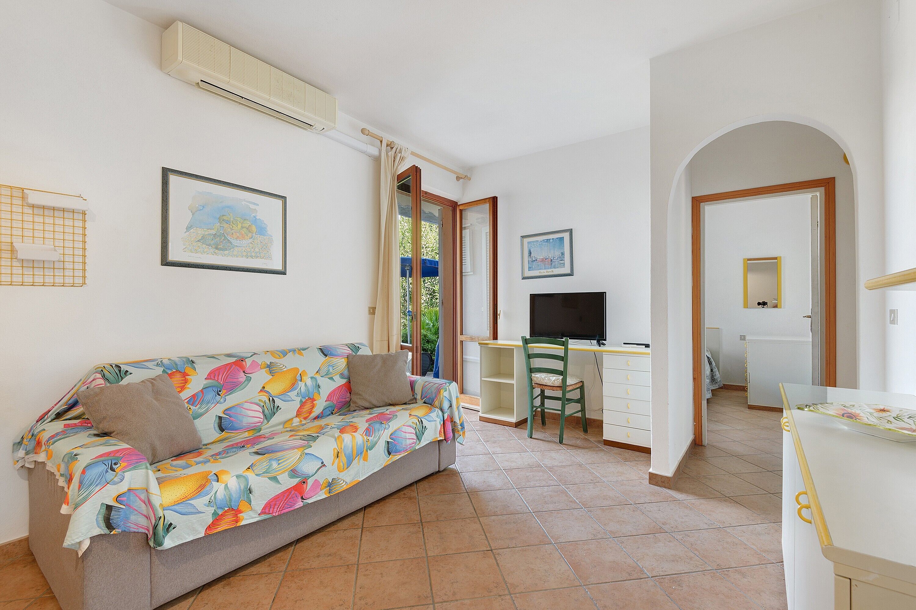 Una habitación con sofá, escritorio, silla y televisión.