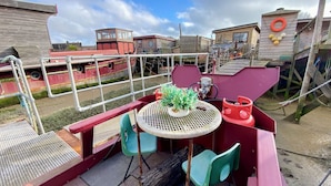 Une terrasse dotée d’une table et de chaises, entourée d’une rambarde et de structures en bois.