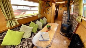 Un intérieur chaleureux avec un banc en bois, des coussins, une table avec un carnet et un poêle à bois.