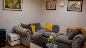 Una sala de estar con un sofá seccional gris, una mesita auxiliar blanca, una mesa de centro negra y un cuadro enmarcado de vida silvestre sobre el sofá.