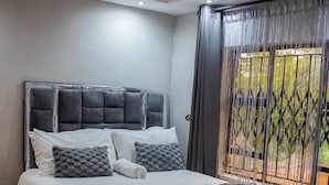 A modern bedroom with a large bed, a headboard, and a ceiling light fixture. - Darwendale Madhuve Lodge for one (Darwendale)