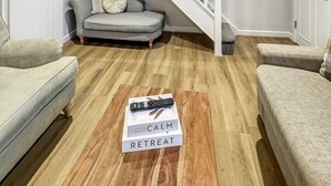 A modern living room with a staircase, wooden flooring, and a remote control on a box. - Sleeps 8 3bedroom House, Harlaxton Garden Driveway (Harlaxton)