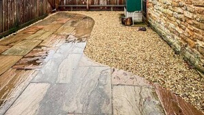 A backyard with a stone patio, a wooden fence, and a stone wall. - Sleeps 8 3bedroom House, Harlaxton Garden Driveway (Harlaxton)