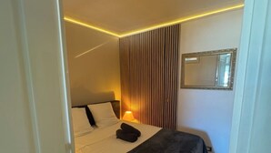 Ein Schlafzimmer mit einem Bett, einer Nachttischlampe, einem Spiegel und einer Tür.