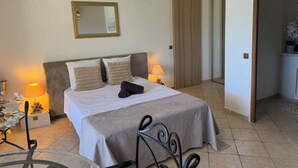 Ein ordentlich eingerichtetes Schlafzimmer mit einem Bett, Nachttischlampen, einem Spiegel und einer Pendelleuchte.