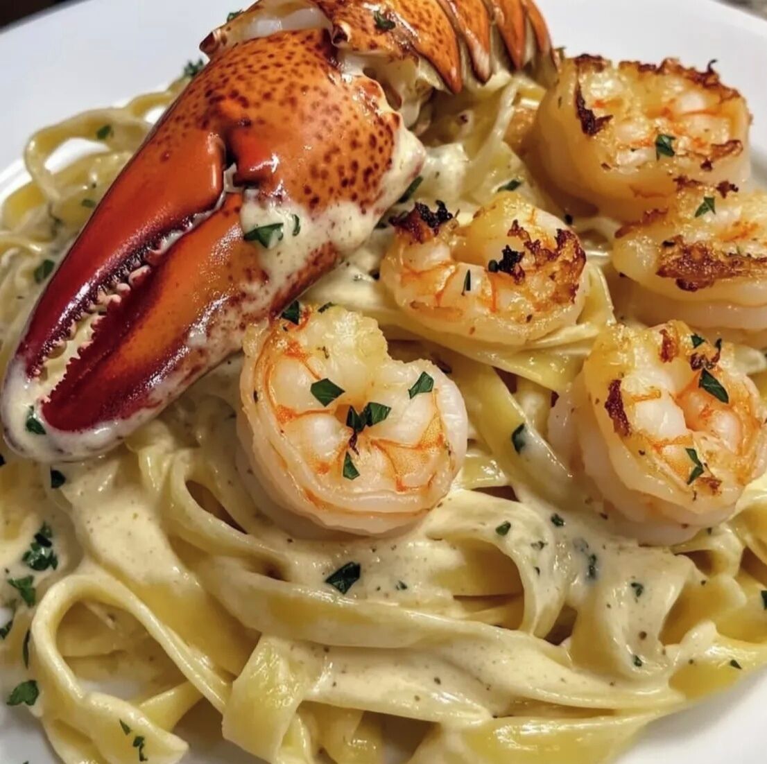 En tallerken med pasta, hummerhale og rejer, pyntet med krydderurter.