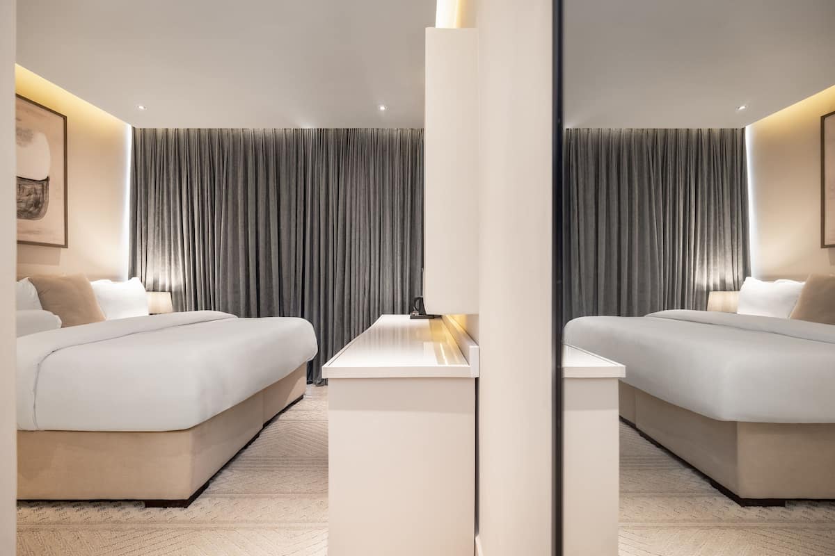 Une chambre d’hôtel moderne avec un grand lit, une table de chevet et un miroir.