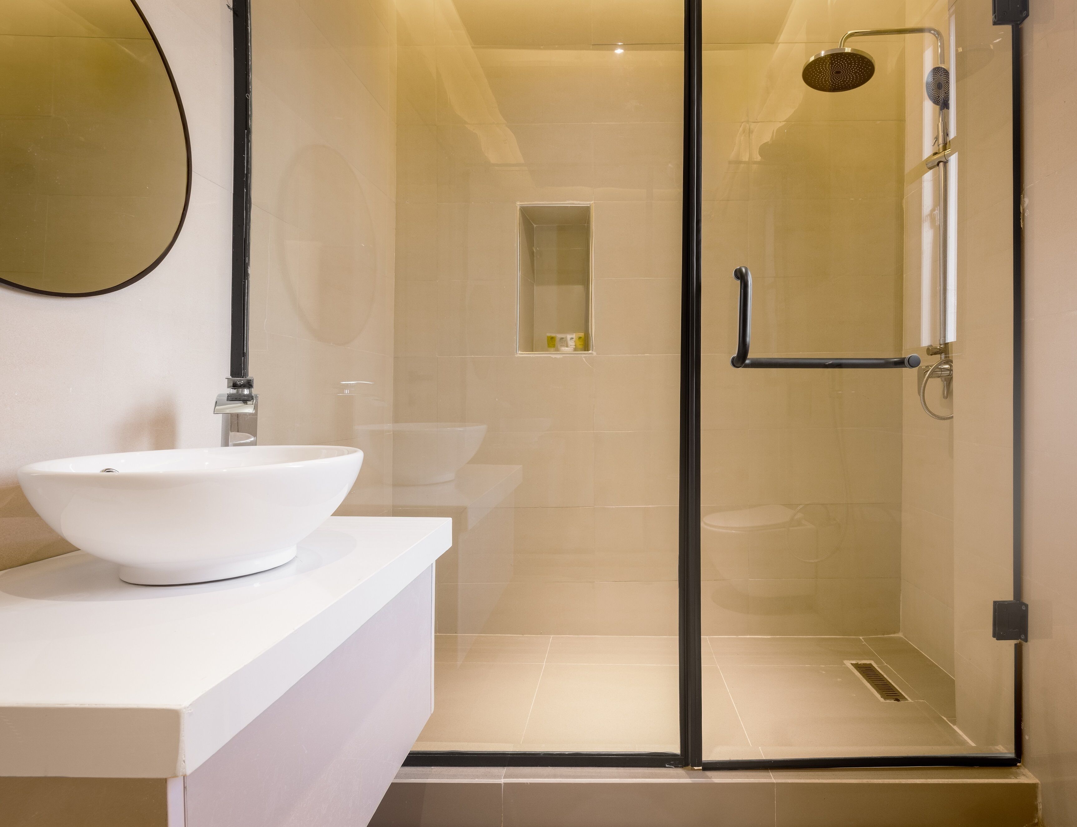 Un baño moderno con un lavamanos blanco, una cabina de ducha de vidrio y un espejo en la pared.