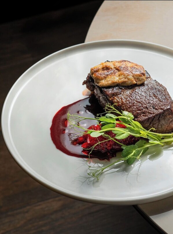 A plate with a steak, a piece of meat, and some greens. - The Palms Classic Hotel (Benin City)
