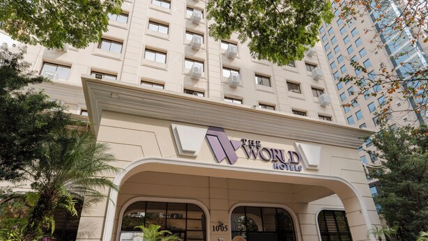 A hotel entrance with a large archway, a sign reading "The World Hotels", and a parking area with a few cars. - The World Hotel by Wecare Hosting (São Paulo)