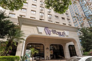 A hotel entrance with a large archway, a sign reading "The World Hotels", and a parking area with a few cars. - The World Hotel by Wecare Hosting (São Paulo)