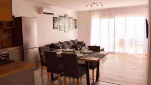 A modern apartment with a dining area, kitchen, and a balcony with large windows. - Holiday apartment with air conditioning and sea view (Novi Vinodolski)