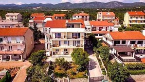 A residential area with multi-story buildings, balconies, and a mountainous backdrop. - Holiday apartment with air conditioning and sea view (Novi Vinodolski)