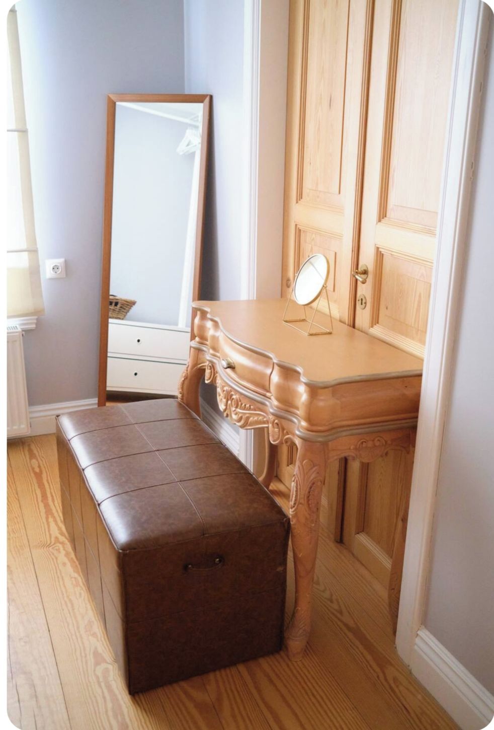 Une chambre à coucher avec une commode en bois, un miroir et un banc.