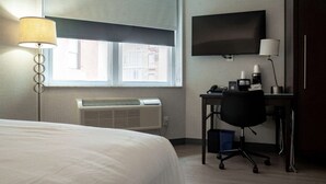 A hotel room with a bed, a desk with a chair, a television, and a window with blinds. - Near One World Trade Center + Free Wi-Fi (New York)