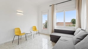 A modern living room with a grey sofa, yellow chairs, a small table, and a balcony with a view. - CASA LAS CALAS (Torrevieja)