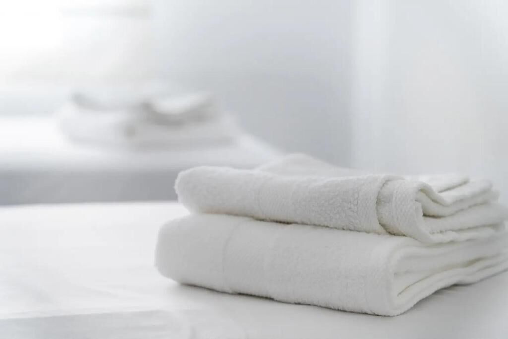 A stack of white towels on a white surface.