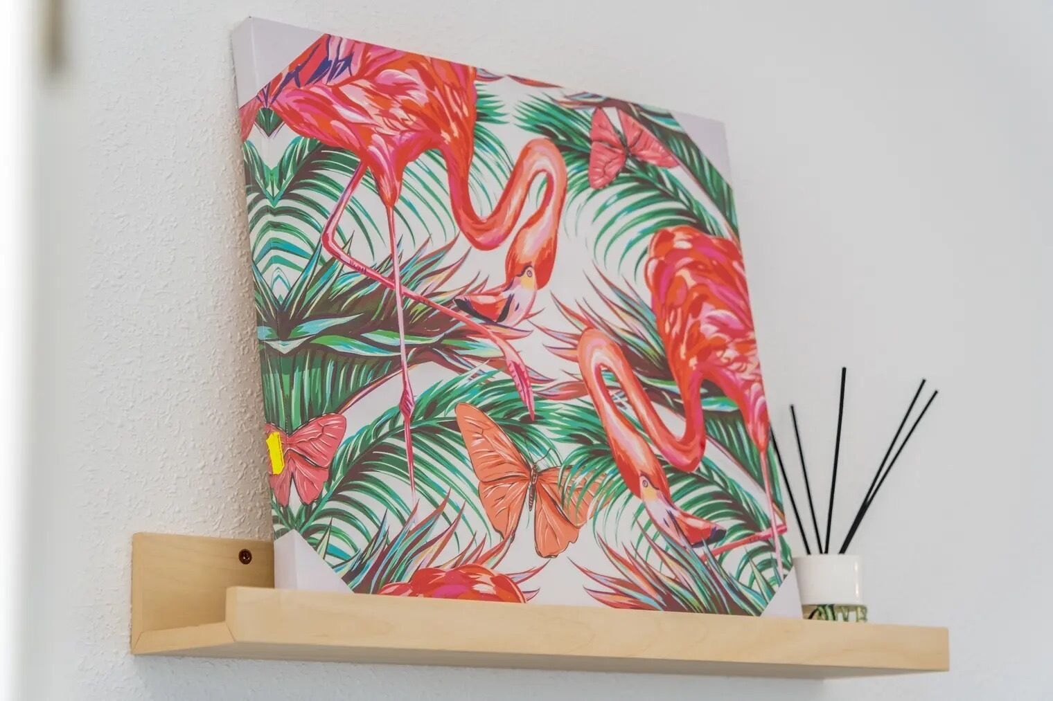 Una pintura de flamencos y hojas tropicales sobre una pared.