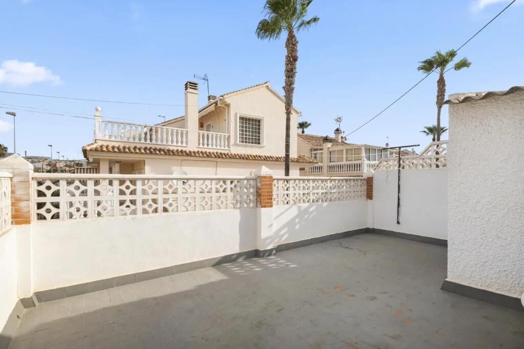 A residential building with a balcony, white walls, and a decorative fence.