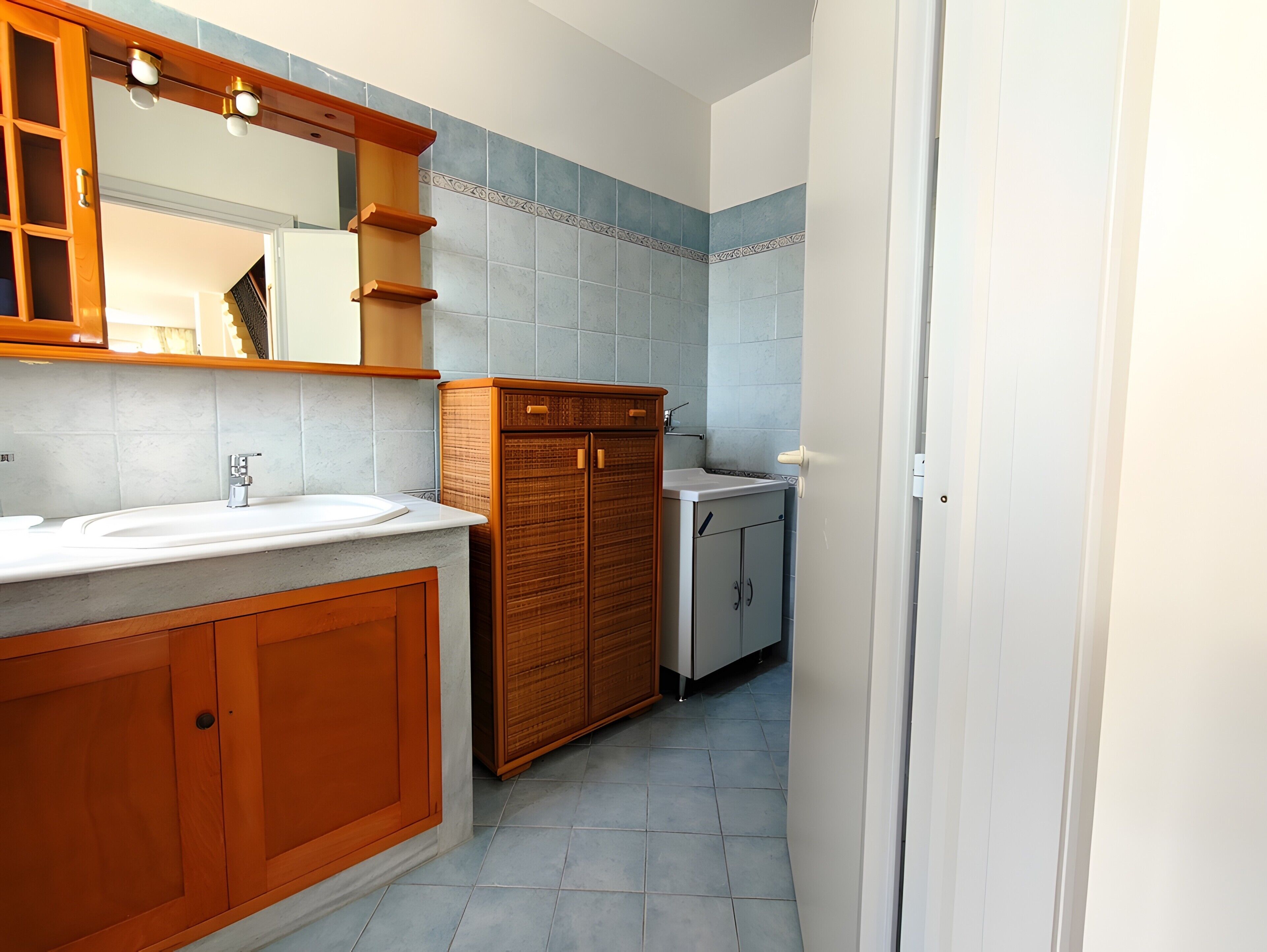 A bathroom with a wooden vanity, a sink, and a mirror.