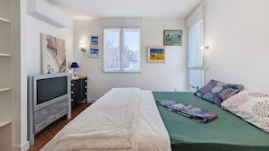 Une chambre à coucher avec un lit, une télévision et des œuvres d’art accrochées aux murs.