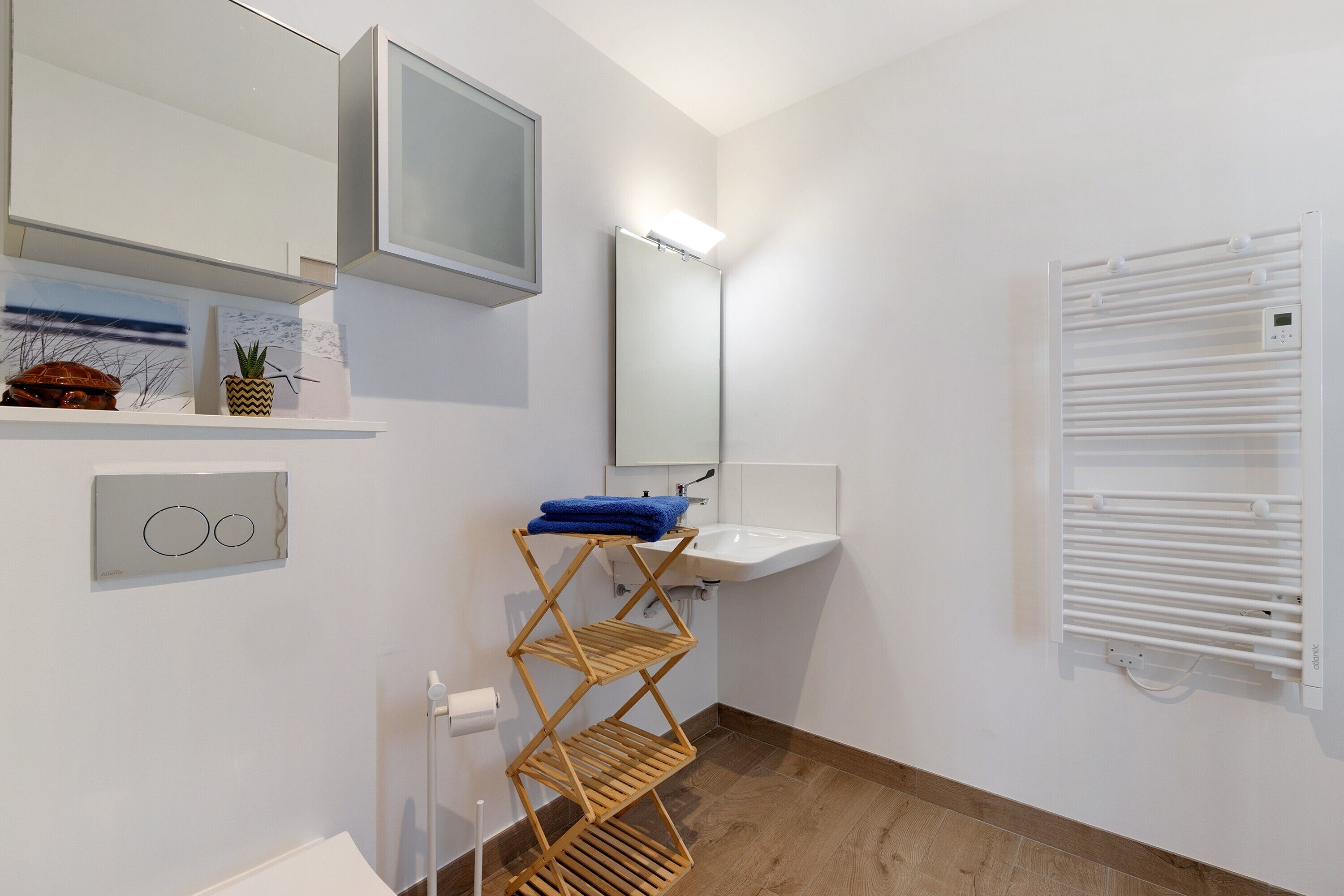 Une salle de bain équipée d’un lavabo, d’un miroir, d’un porte-serviettes et d’un radiateur fixé au mur.
