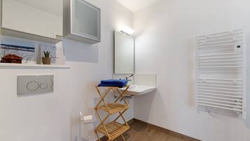 Une salle de bain équipée d’un lavabo, d’un miroir, d’un porte-serviettes et d’un radiateur fixé au mur.