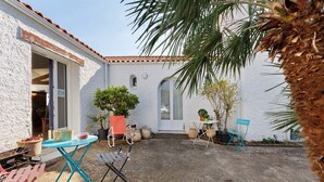 A courtyard with a white building, a palm tree, and outdoor furniture.