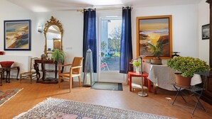 A living room with a large mirror, a dining table, chairs, a sofa, a coffee table, and a potted plant.