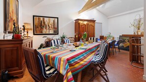 A dining area with a long table, striped tablecloth, and wooden chairs.