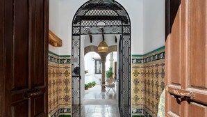An arched doorway with intricate metalwork, leading to a courtyard with a tiled floor and a table with chairs. - Exclusive 5 Rooms Traditional House in Cordoba. Casa San Pedro (Córdoba)
