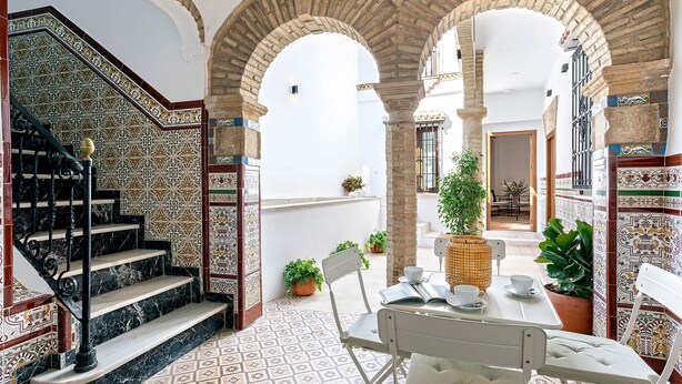 A courtyard with a tiled floor, a staircase, and a table with chairs. - Exclusive 5 Rooms Traditional House in Cordoba. Casa San Pedro (Córdoba)