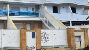 Ein mehrgeschossiges Wohngebäude mit Treppe, geschlossenem Eingangsbereich und einem Balkon.