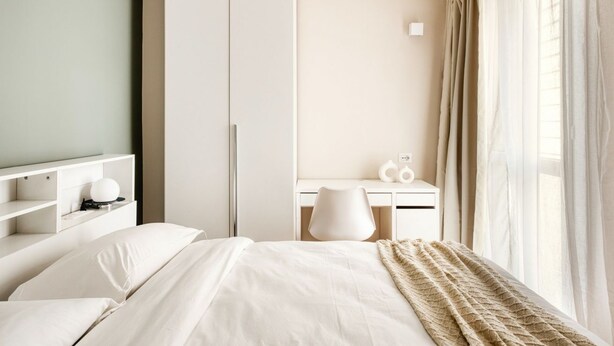 Een hotelkamer met een bed, een bureau, een kledingkast en een raam met gordijnen.