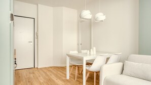 Een moderne, minimalistische kamer met een houten vloer, witte meubels en hanglampen.